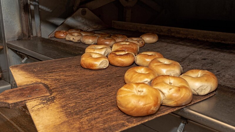 Fresh bagels being taken out of an oven