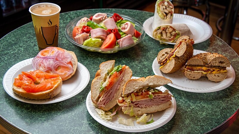 Salad, coffee and multiple sandwiches with focus on ham and cheese sandwich