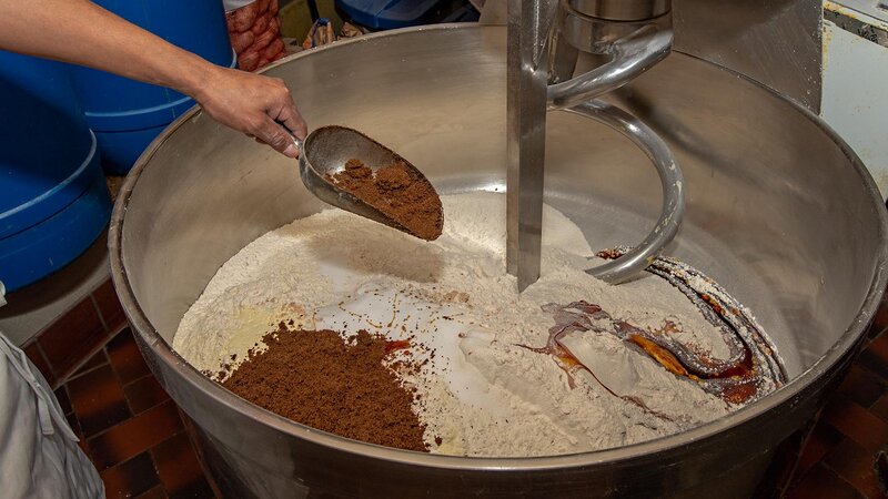 Brown sugar being poured into a large mixing bowl