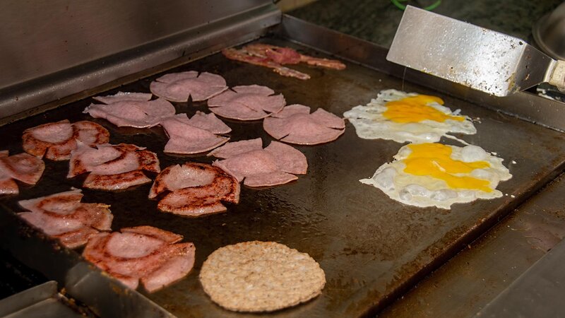 Griddle cooking eggs, taylor ham and sausage patty